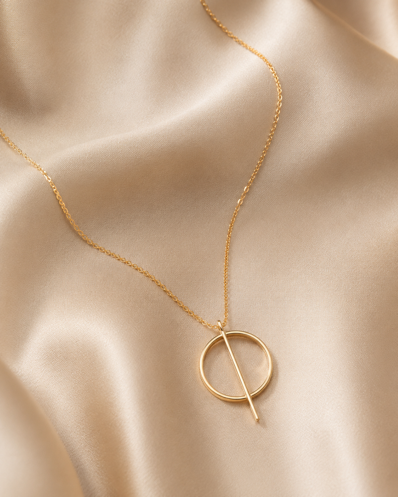 Gold necklace with a circular pendant on a beige fabric background