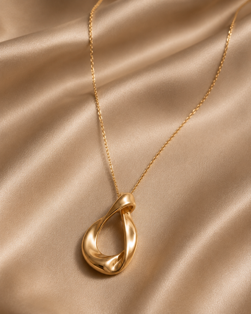 Gold necklace with a pendant on a beige fabric background
